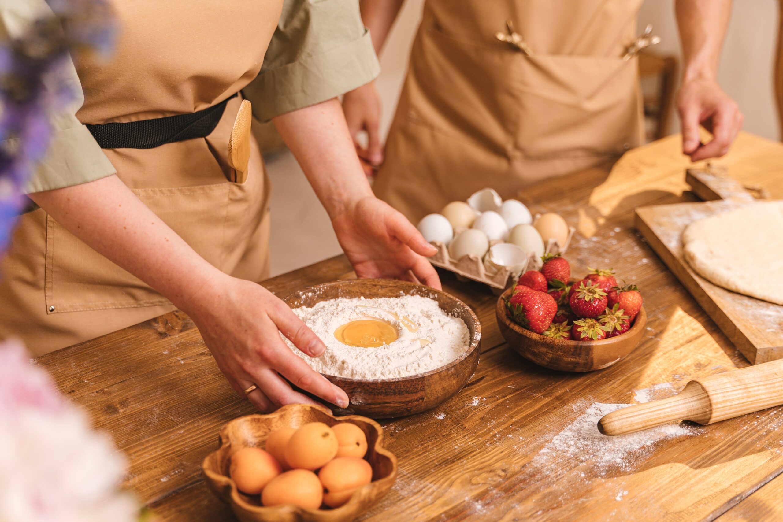 person holding a wooden bowl with flour and egg