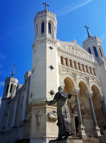 Basilique Notre Dame de Fourviere, white church, blue sky, a monument wearing black, cross