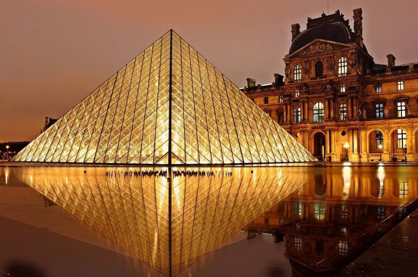 Louvre Museum, a bright pyramid, a building behind the pyramid