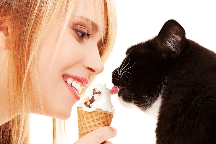 A lady feeding ice cream to a cat
