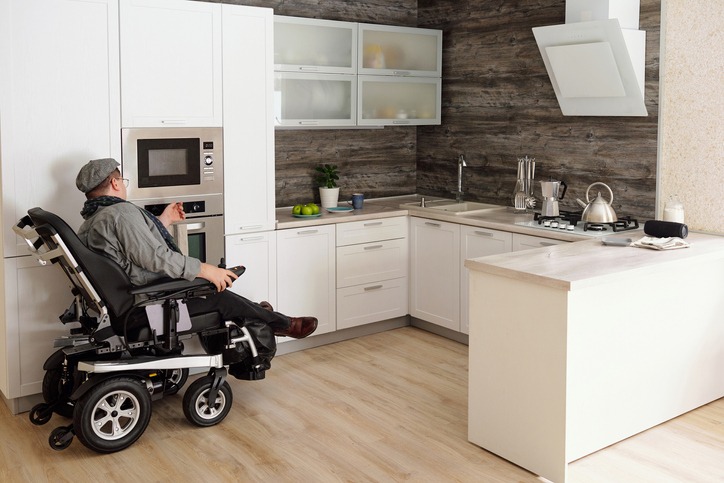 Middle aged man with disability sitting by electric oven