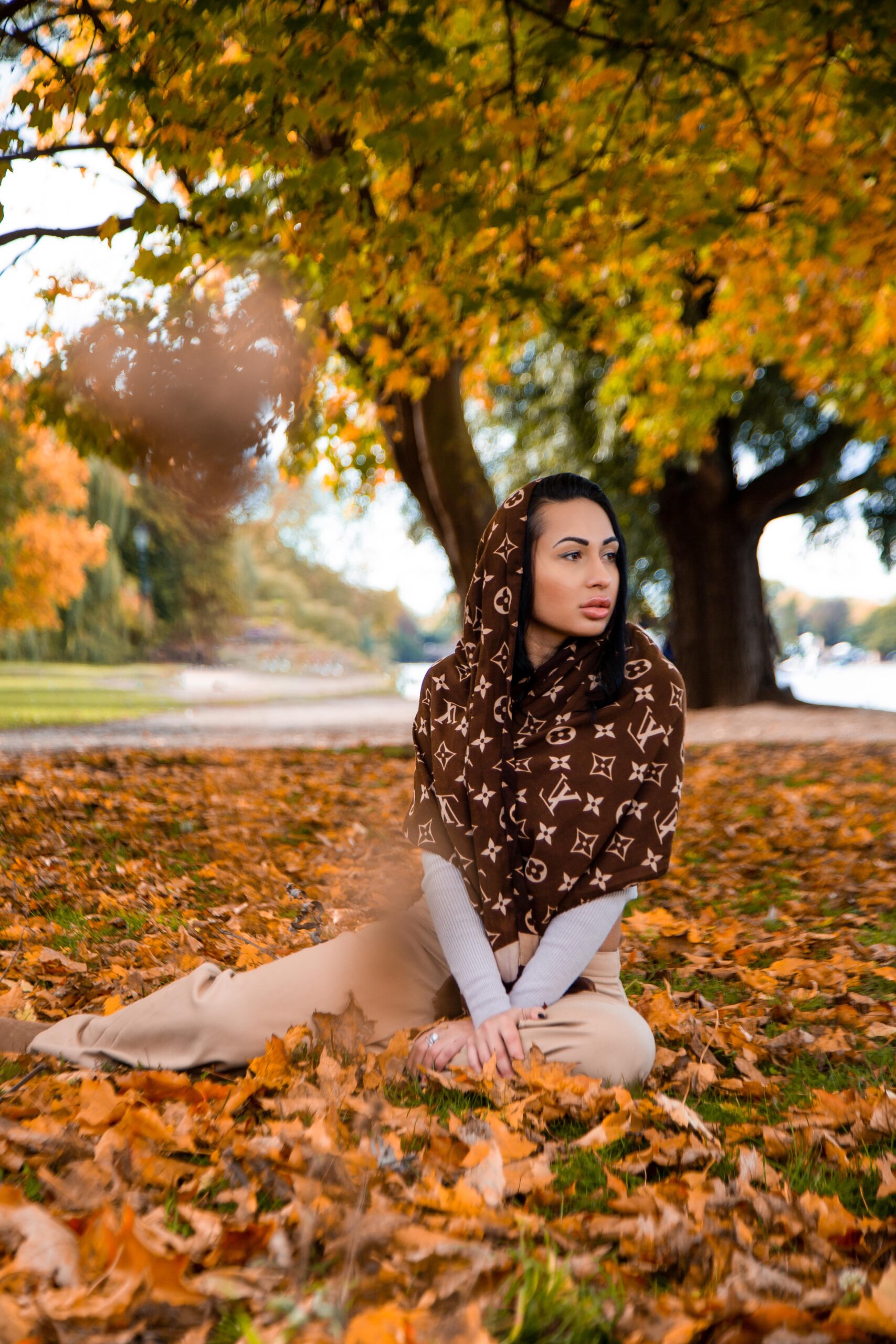 Woman with Louis Vuitton Scarf Sitting on Fallen Leaves 